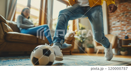 husband playing soccer with wife at home, man play football with woman at living room, person kick ball 120000787