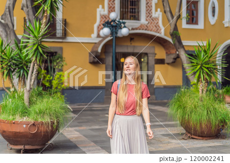 Female tourist walking through the colorful colonial streets of Puebla, Mexico. Travel, cultural exploration, and vibrant architecture concept 120002241