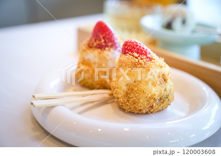 Two pieces of daifuku mochi topped with strawberries are sitting on a white plate Two pieces of daifuku mochi topped with strawberries are sitting on a white plate 120003608