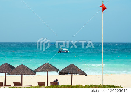 Couple enjoying tropical paradise beach with red warning flag 120003612