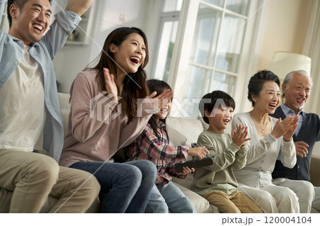 happy three generation asian family sitting on couch watching sport game on tv happy three generation asian family sitting on couch watching sport game on tv 120004104