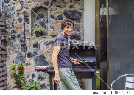Man cooking dinner on a barbecue in his backyard. Outdoor cooking, home lifestyle, and family time concept 120004186