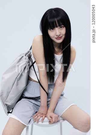Korean Woman in Her 20s Poses Sitting on Chair in Block Core fashion 120005043