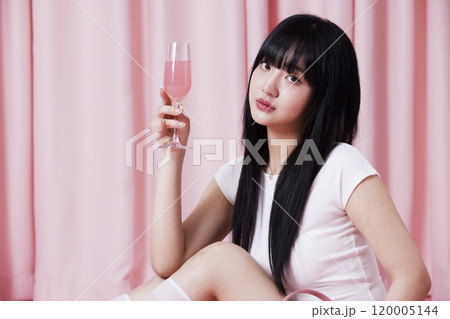 A Korean woman in her 20s holding a champagne glass with a pink drink on a pink background A Korean woman in her 20s holding a champagne glass with a pink drink on a pink background 120005144