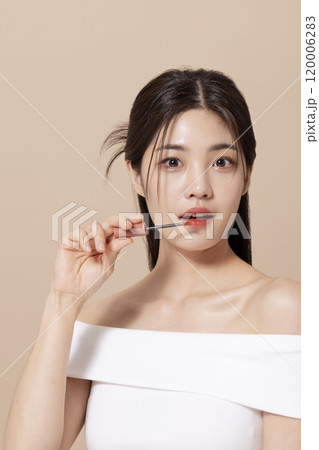 a woman in her 20s holding cosmetics in front of a table decorated with flowers 120006283
