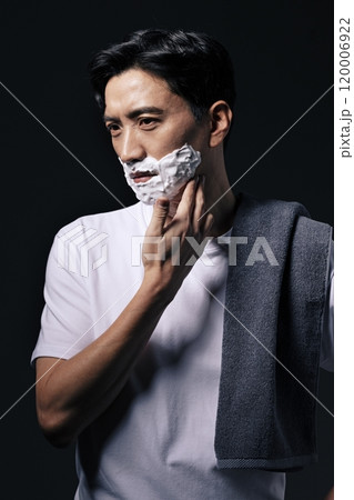 Middleaged man applying shaving cream to his face with one hand Middleaged man applying shaving cream to his face with one hand 120006922