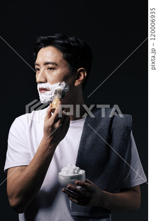 Middleaged man applying foam to his face with a shaving brush 120006935