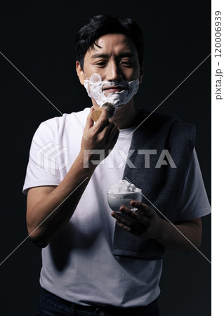 Middleaged man applying foam to his chin with a shaving brush 120006939