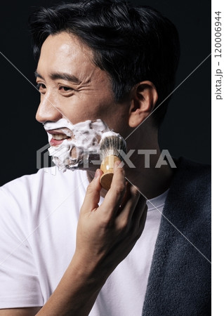 Middleaged man applying foam to his face with a shaving brush 120006944