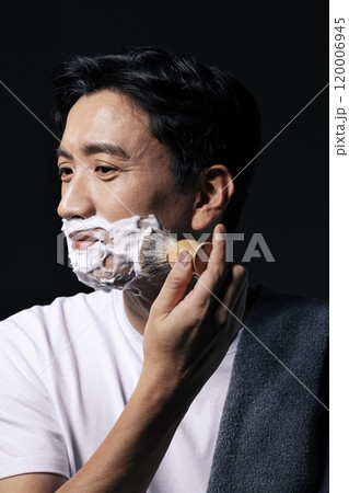 Middleaged man applying foam to his face with a shaving brush Middleaged man applying foam to his face with a shaving brush 120006945