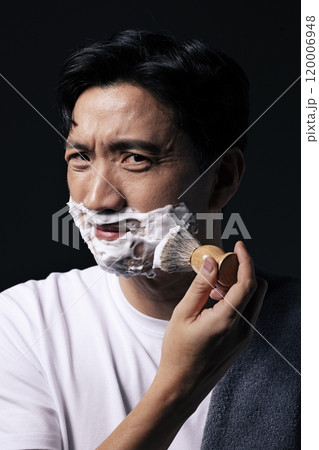 Middleaged man applying foam to his face with a shaving brush Middleaged man applying foam to his face with a shaving brush 120006948