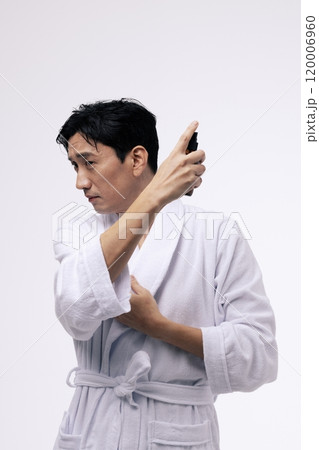 A middleaged man who holds a spray bottle and sprays mist A middleaged man who holds a spray bottle and sprays mist 120006960