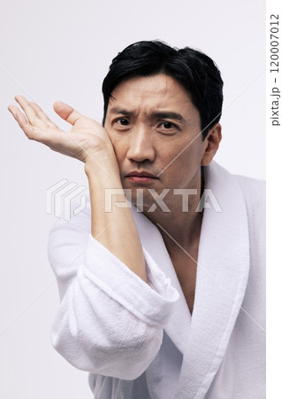 Middleaged man putting his wrist to his cheek Middleaged man putting his wrist to his cheek 120007012