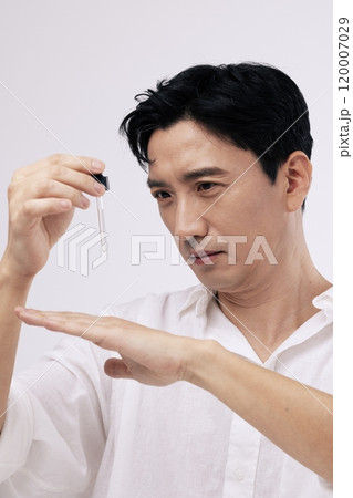 A middleaged man dropping an ampoule on the back of his hand A middleaged man dropping an ampoule on the back of his hand 120007029