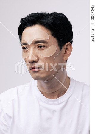 Middleaged man with cosmetic patches around his eyes 120007043
