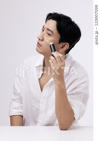Middleaged man applying foundation to his face 120007099