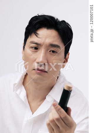 Middleaged man looking at stick foundation 120007101