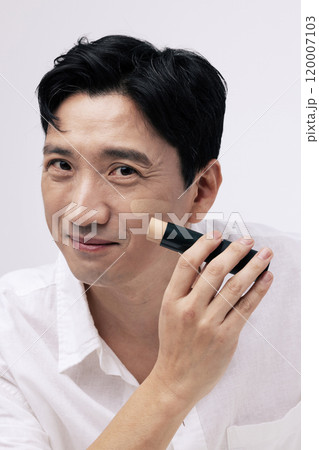Middleaged man smiling and applying foundation to his face Middleaged man smiling and applying foundation to his face 120007103