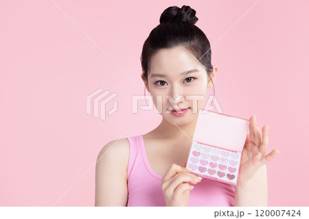 A teenage woman posing with an eyeshadow palette 120007424