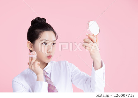 A teenage woman wearing a school uniform and holding cosmetics in a cute pose A teenage woman wearing a school uniform and holding cosmetics in a cute pose 120007718