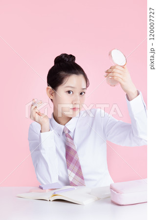 A teenage woman wearing a school uniform and holding cosmetics in a cute pose 120007727