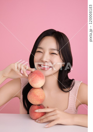 A woman in her 20s posing with a peach on the table A woman in her 20s posing with a peach on the table 120008183