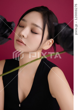 A woman in her 20s posing in front of black poppy flowers 120008276