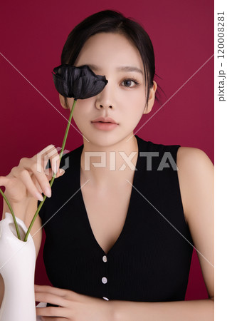 A woman in her 20s posing in front of black poppy flowers 120008281