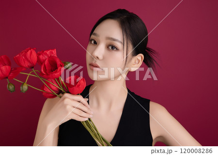 A woman in her 20s posing with a red poppy flower 120008286