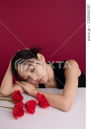 A woman in her 20s posing with a red poppy flower A woman in her 20s posing with a red poppy flower 120008297