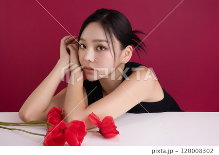 A woman in her 20s posing with a red poppy flower A woman in her 20s posing with a red poppy flower 120008302