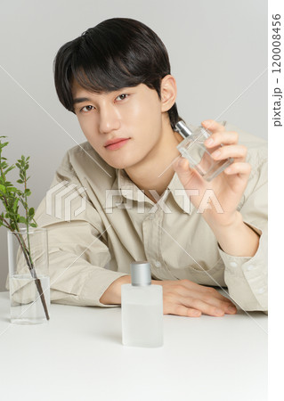A man in his 20s posing with a perfume bottle A man in his 20s posing with a perfume bottle 120008456