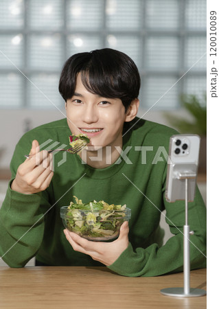 A man in his 20s managing his diet by eating salad 120010089
