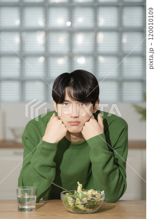 A man in his 20s managing his diet by eating salad 120010109
