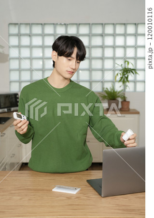 A man in his 20s uses a laptop to look up information to manage blood sugar levels 120010116