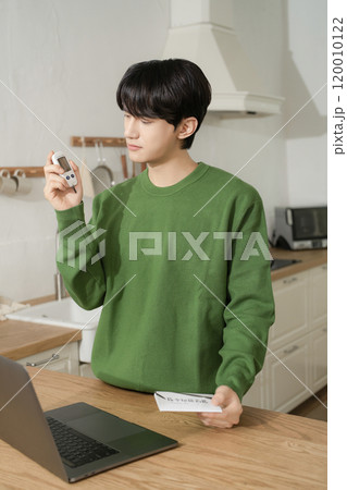 A man in his 20s uses a laptop to look up information to manage blood sugar levels 120010122