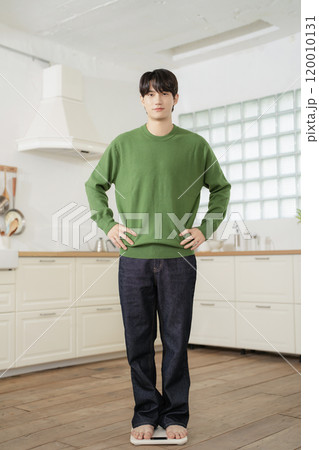 A man in his 20s measuring his weight on a scale A man in his 20s measuring his weight on a scale 120010131