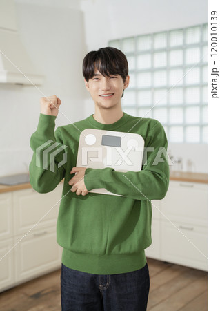 A man in his 20s holding a scale and making a resolution A man in his 20s holding a scale and making a resolution 120010139