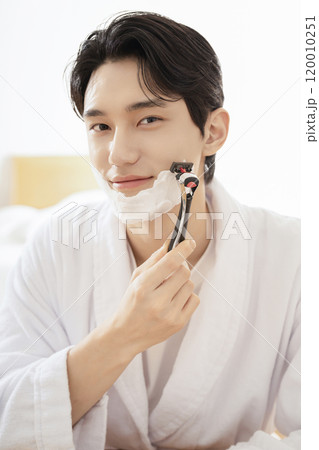 A man in his 20s shaving in front of a mirror A man in his 20s shaving in front of a mirror 120010251
