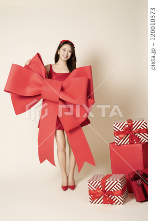 A woman in her 20s next to a gift with a large ribbon 120010373