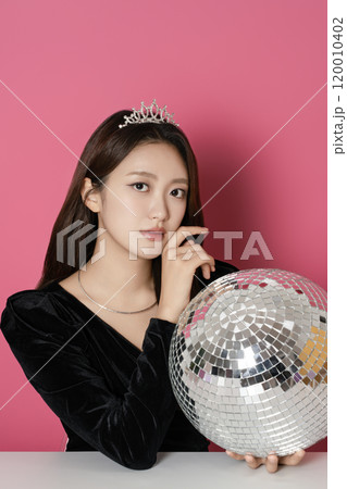 A woman in her 20s posing in front of a mirror ball A woman in her 20s posing in front of a mirror ball 120010402