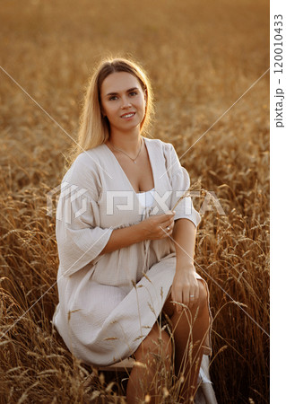 A woman is sitting in a field of tall grass A woman is sitting in a field of tall grass 120010433
