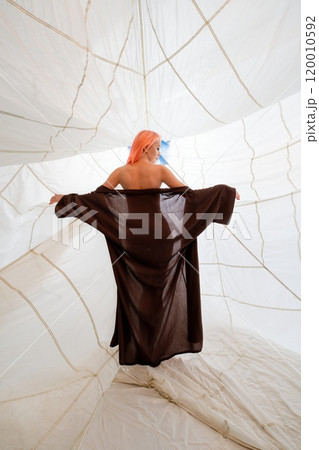Woman With Pink Hair Wearing Brown Robe Inside White Inflatable Structure Woman With Pink Hair Wearing Brown Robe Inside White Inflatable Structure 120010592