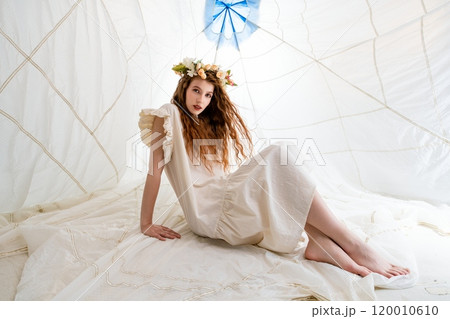 Young Woman Wearing Floral Crown Sitting Inside a White Tent 120010610