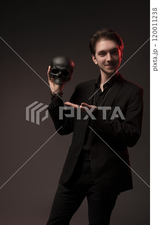 Man in black suit smile with skull in hands look at camera Man in black suit smile with skull in hands look at camera 120011238