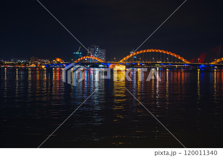 Panorama of Dragon Bridge or Cau Rong Bridge over Han River in Da Nang in Vietnam at night with a golden backlight 120011340