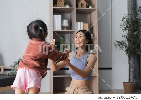 Mother and Child Practicing Yoga Together at Home in a Bright and Cozy Living Room Setting 120011475