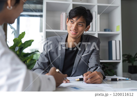 Businessman Signing Contract Agreement in Modern Office Setting with Colleague Businessman Signing Contract Agreement in Modern Office Setting with Colleague 120011612