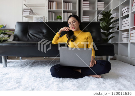 Young Woman Relaxing Happily in Modern Living Room with Laptop, Enjoying Leisure Time on Comfortable Sofa 120011636