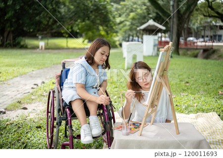 Close Friends, Disabled Young Women Drawing Together Outdoors in a Park on a Sunny Day, Embracing Creativity and Friendship 120011693
